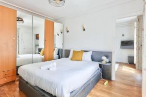 1 dormitorio con 1 cama blanca grande y espejo en Superbe T2 au cœur du 17ᵉ arrondissement, en París