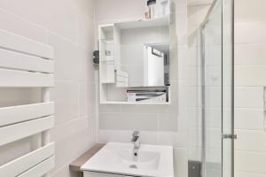 Baño blanco con lavabo y espejo en Superbe T2 au cœur du 17ᵉ arrondissement, en París