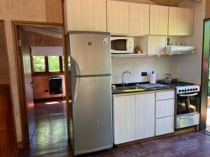 a kitchen with a refrigerator and a microwave at Cabaña La Morocha in Ostende