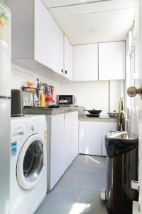 eine Küche mit weißen Schränken, einer Waschmaschine und einem Trockner in der Unterkunft Student Accommodation - 294 Hennessy Road in Hongkong