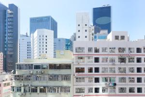 een hoog wit gebouw in een stad met hoge gebouwen bij Student Accommodation - 294 Hennessy Road in Hong Kong