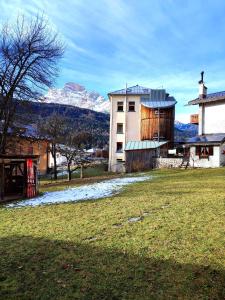 a field with a building and mountains in the background at Appartamento Pelmo in Borca di Cadore