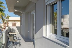 ヘルソニソスにあるNisimos Modern Apartmentのバルコニー(椅子、テーブル付)、窓が備わります。