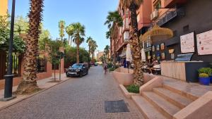 a street with palm trees and a car parked on the street at Apartamento en Majorelle, Marrakech. in Marrakesh