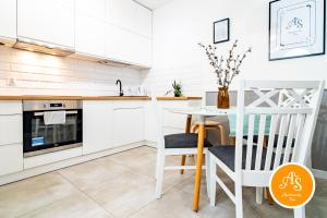 a kitchen with white cabinets and a table and chairs at ApartamentySnu, Wola Komfort IV z parkingiem in Warsaw