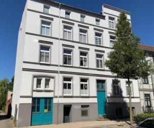 a white building with blue doors on a street at City-Apartment 1 in Schwerin