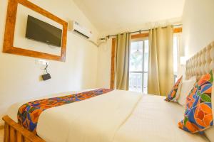 a bedroom with a bed with a tv on the wall at FabHotel Grand Royal Palms in Benaulim