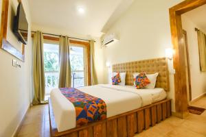 a bedroom with a large bed and a window at FabHotel Grand Royal Palms in Benaulim