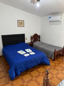 um quarto com 2 camas e uma colcha azul em 4 Ases Hotel em Embalse