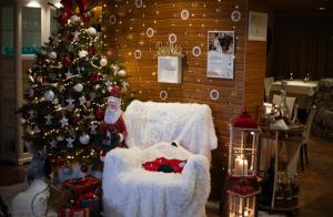 Casa Valcellina Hotel Ristorante في Montereale Valcellina: غرفة عيد الميلاد مع كرسي ثلج وشجرة عيد الميلاد