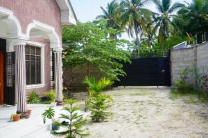 a house with a fence and a courtyard with plants at 2 Bedroom spacious Cozy Home in Kigamboni,10 min Walk to Beach in Dar es Salaam