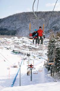 two people on a ski lift in the snow at 一棟貸宿　奥入瀬屋 in Yakeyama