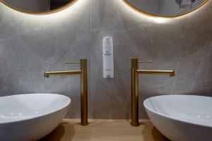 a bathroom with two white sinks and two mirrors at Num Suites & Lofts Athens in Athens