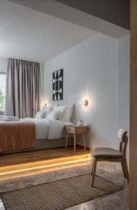 a bedroom with a bed and a table and a chair at Num Suites & Lofts Athens in Athens