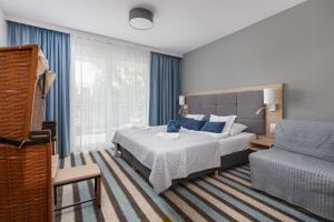 een slaapkamer met een bed, een bank en een stoel bij Sunny Apartments in Bel Mare Resort by Noclegi Renters in Międzyzdroje