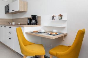 una cocina con 2 sillas amarillas y una barra en Sunny Apartments in Bel Mare Resort by Renters en Międzyzdroje