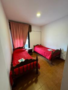 um quarto com 2 camas e uma janela com lençóis vermelhos em 4 Ases Hotel em Embalse