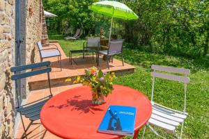 グレーヴェ・イン・キアンティにあるLa Casa Nel Bosco D'arte- Greve in Chianti, holiday house with private gardenの本が置かれた赤いテーブル、椅子、傘