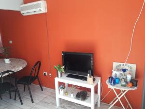 TV en un stand en una habitación con una pared de color naranja en La Delia en Gualeguaychú