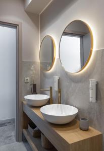 two sinks in a bathroom with two mirrors at Num Suites & Lofts Athens in Athens