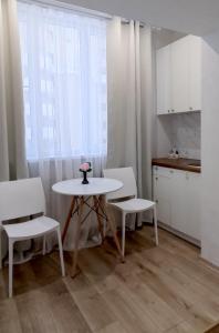 a kitchen with a table and two chairs and a table at Белая студия на Южном вокзале in Kharkiv