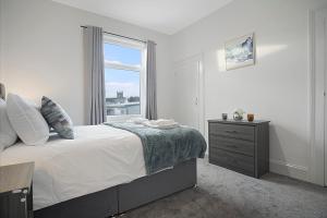 a white bedroom with a bed and a window at Spacious Retreat with Backyard Bliss, Sleeps 7 in Bishop Auckland