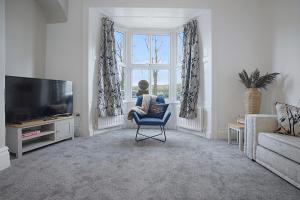 ein Wohnzimmer mit einem Stuhl und einem TV in der Unterkunft Spacious Retreat with Backyard Bliss, Sleeps 7 in Bishop Auckland