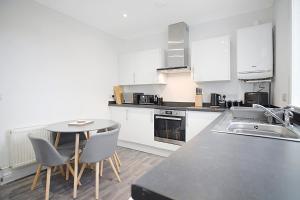 a kitchen with white cabinets and a table and chairs at Spacious Retreat with Backyard Bliss, Sleeps 7 in Bishop Auckland