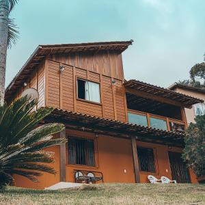 a wooden house with windows and a palm tree at Chalés Requinte em Pedra Azul in Pedra Azul