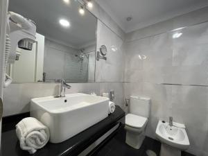 a white bathroom with a sink and a toilet at Hotel Plaza Cavana in Nerja