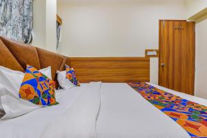 ein Schlafzimmer mit einem großen weißen Bett mit bunten Kissen in der Unterkunft FabExpress Silver Inn in Ahmedabad