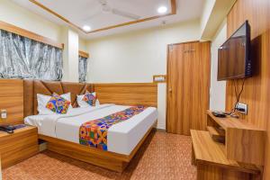 Schlafzimmer mit einem Bett und einem Flachbild-TV in der Unterkunft FabExpress Silver Inn in Ahmedabad