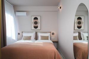 a bedroom with two beds and a mirror at Num Suites & Lofts Athens in Athens
