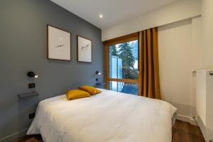 a bedroom with a bed with yellow pillows and a window at Sweet Home Brevent - Happy Rentals in Chamonix