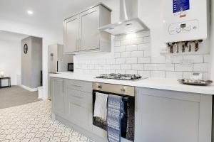 a kitchen with white cabinets and a stove top oven at Dean St Retreat - Cosy Urban Escape, Sleeps 5 in Hexham