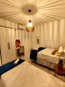 a bedroom with two beds and a chandelier at Ap8 atrás da Passarela do caranguejo- Orla de Atalaia in Aracaju