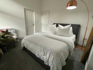 a bedroom with a bed with a white comforter at Orange Rentals- Cosy Apartment- Free Parking! in Liverpool