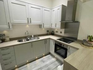 a kitchen with white cabinets and a sink and a stove at Orange Rentals- Cosy Apartment- Free Parking! in Liverpool