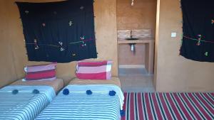 a living room with two beds and a wall with decorations at Mhamid yaya camp in Mhamid