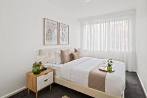 um quarto branco com uma cama grande e uma mesa em The Elsternwick Abode em Melbourne