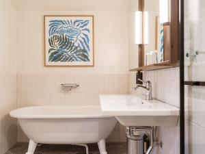 een badkamer met een wastafel en een wit bad bij Elite Hotel Mårtenson in Halmstad