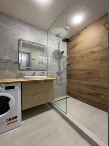 a bathroom with a shower and a sink and a washing machine at Nafta APARTS in Skhidnitsa +174 photos