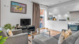 a living room with two couches and a kitchen at Modern apartments close to Colombia Road Market in London