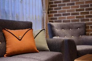 an orange pillow sitting on a couch next to two chairs at Sunshine B&B in Jiufen