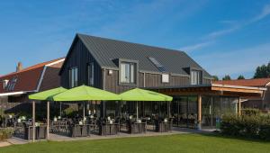 ein Gebäude mit Tischen und grünen Sonnenschirmen in der Unterkunft B&B Restaurant Maria Johanna Hoeve in Noordeloos