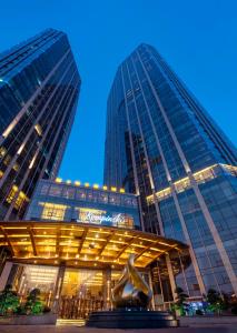 a building with a statue in front of it with two tall buildings at Kempinski Hotel Changsha in Changsha