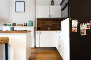 a kitchen with white cabinets and a black refrigerator at Chez Louise et Paul, l'Appart du Centre in Dinan
