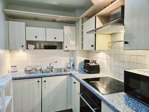 a kitchen with white cabinets and a sink at ABBA Corner in London