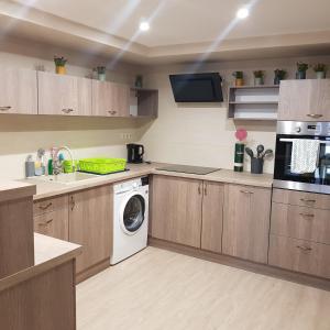 a kitchen with wooden cabinets and a washing machine at Mamacita stúdió apartman in Győrújbarát