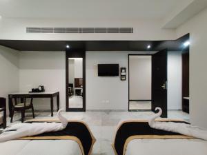 pokój hotelowy z 2 łóżkami i stołem w obiekcie Hotel Saratharajans w mieście Maduraj